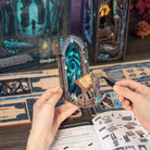 Hænder holder samlet CUTEBEE DIY Book Nook Kit – The Gate of Wonderland-port med spiralportal og lille skrin